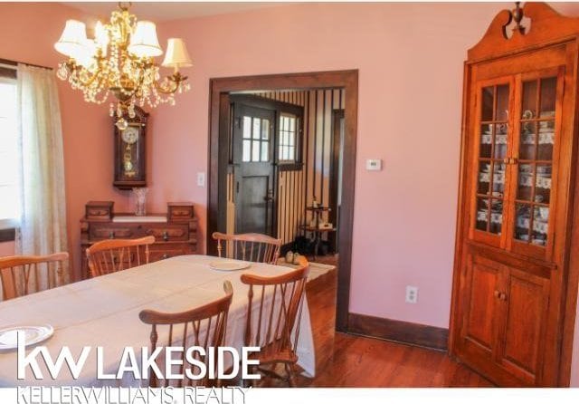 dining area with dark wood-type flooring and an inviting chandelier