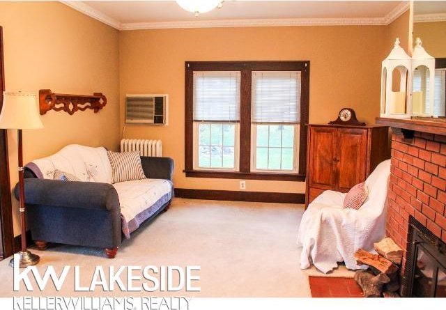 living room featuring ornamental molding, radiator heating unit, a fireplace, and carpet flooring