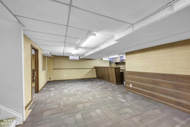 basement with a paneled ceiling and carpet floors