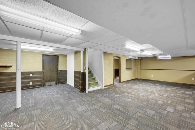 basement with a paneled ceiling and carpet floors