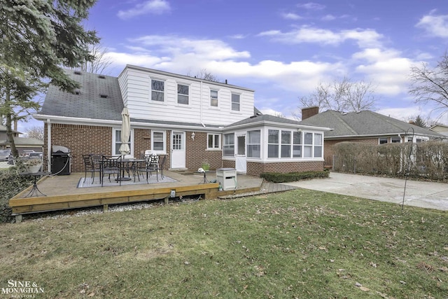 back of property featuring a yard, a deck, and a sunroom