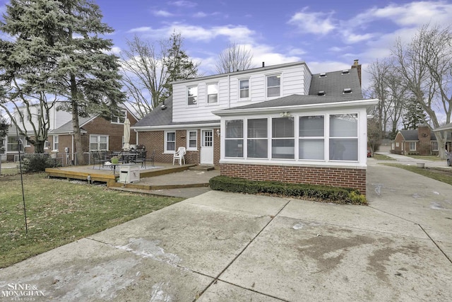 view of front property featuring a patio, a deck, a front lawn, and a sunroom