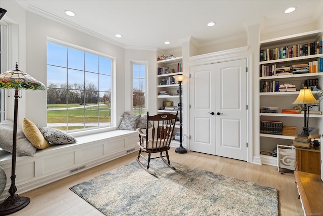 sitting room with crown molding and light hardwood / wood-style flooring