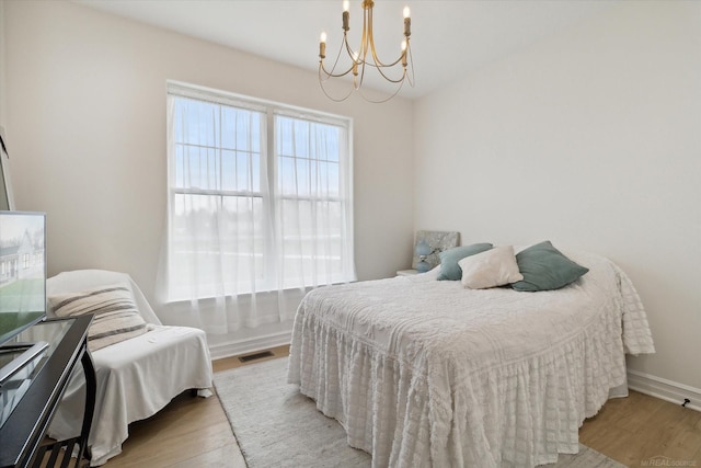 bedroom with a notable chandelier and light wood-type flooring