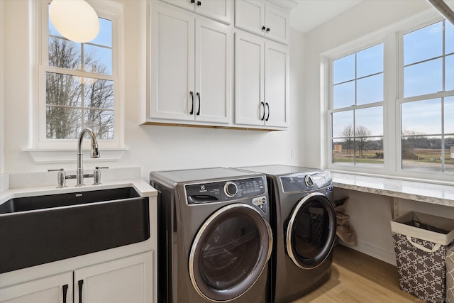 laundry room featuring cabinets, sink, independent washer and dryer, and light wood-type flooring