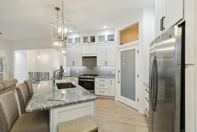 kitchen with sink, appliances with stainless steel finishes, white cabinetry, a kitchen breakfast bar, and an island with sink