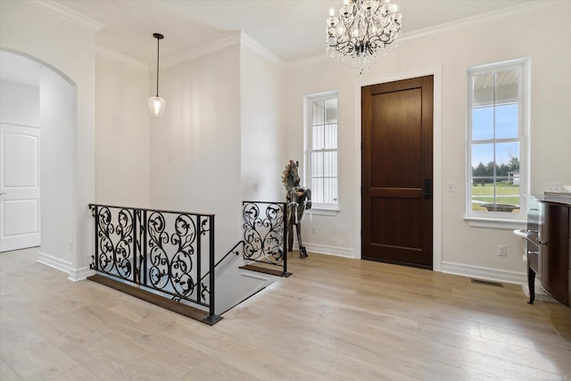 foyer entrance featuring an inviting chandelier, ornamental molding, and light hardwood / wood-style floors