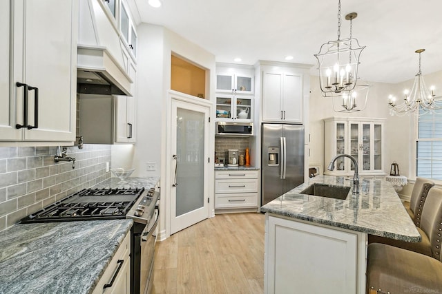 kitchen featuring sink, stainless steel appliances, a kitchen breakfast bar, an island with sink, and white cabinets