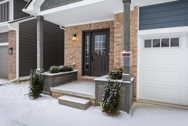 snow covered property entrance featuring a garage