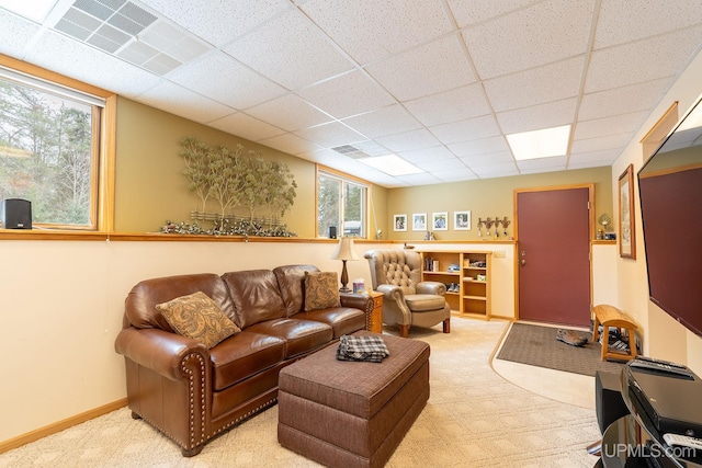 living room with a paneled ceiling and light colored carpet