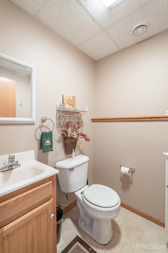 bathroom with vanity, toilet, and a drop ceiling