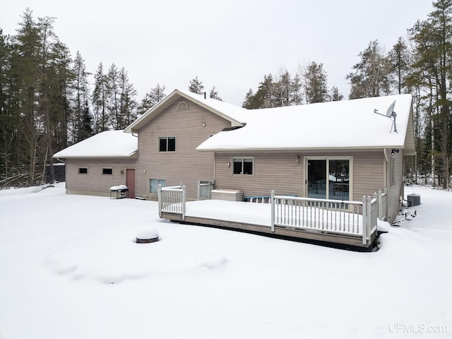 snow covered house with a deck and central air condition unit