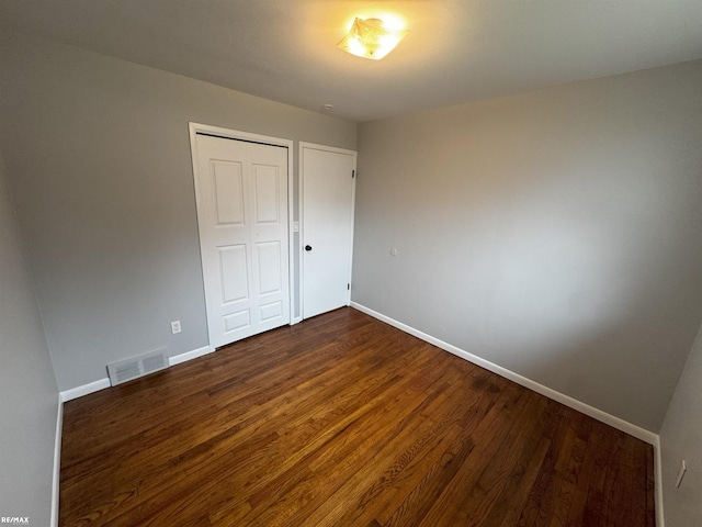 unfurnished bedroom with dark wood-type flooring and a closet