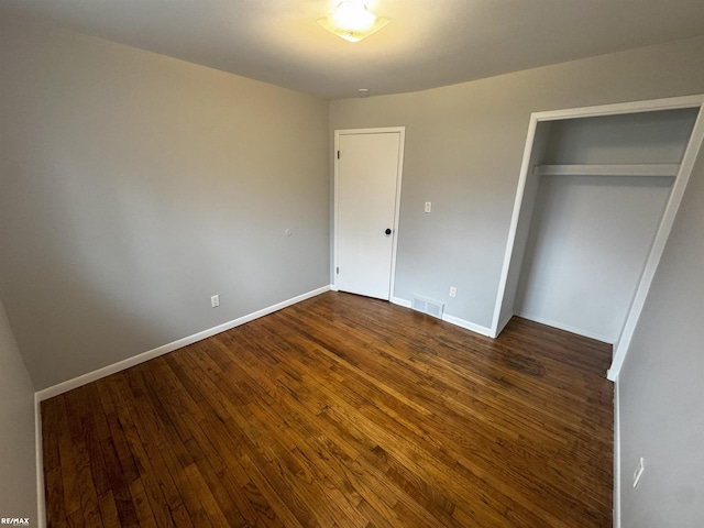 unfurnished bedroom featuring a closet and dark hardwood / wood-style floors