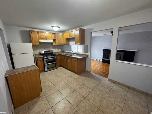 kitchen with sink, white refrigerator, ceiling fan, range with two ovens, and backsplash