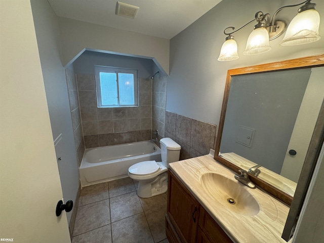 full bathroom featuring tile patterned flooring, tile walls, vanity, tiled shower / bath, and toilet