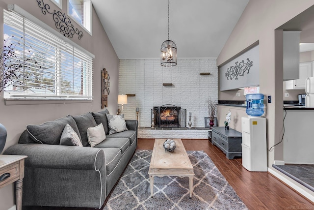 living room with high vaulted ceiling, dark hardwood / wood-style floors, a chandelier, and a fireplace