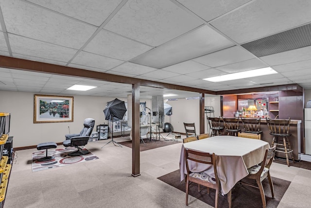 game room with bar, light carpet, and a drop ceiling