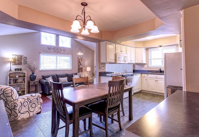 dining room featuring vaulted ceiling, a chandelier, and sink