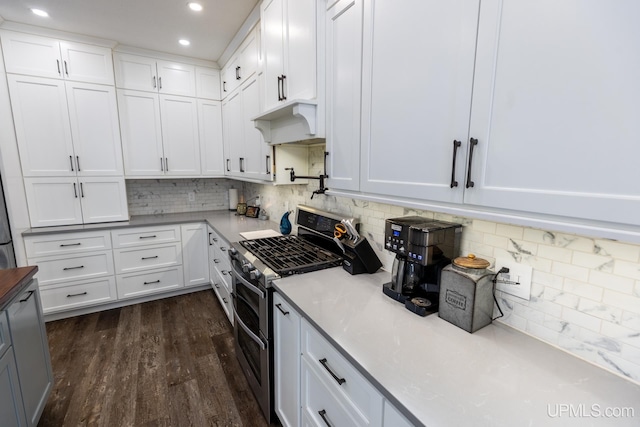 kitchen featuring double oven range, backsplash, white cabinets, and dark hardwood / wood-style flooring