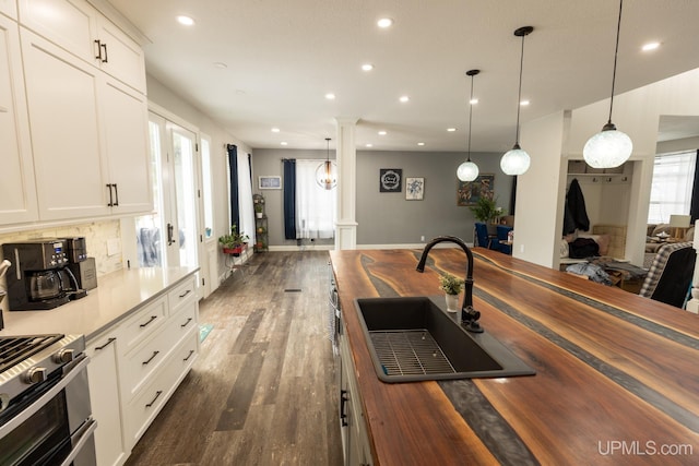 kitchen featuring pendant lighting, white cabinetry, sink, and decorative columns