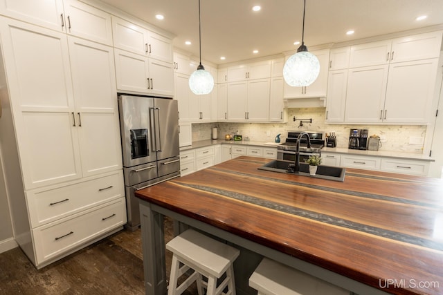 kitchen featuring butcher block counters, decorative light fixtures, high end refrigerator, and white cabinetry