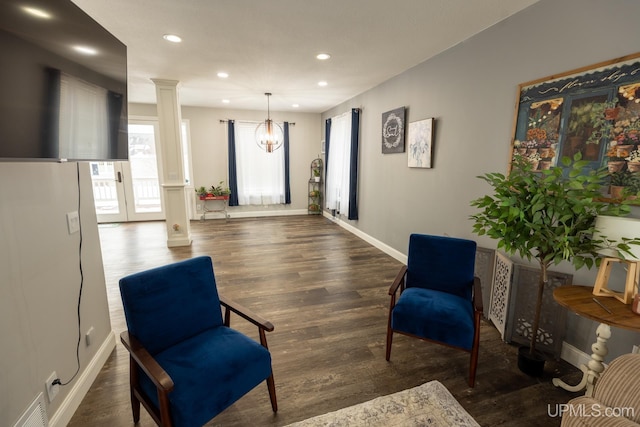 living area featuring decorative columns and dark hardwood / wood-style flooring