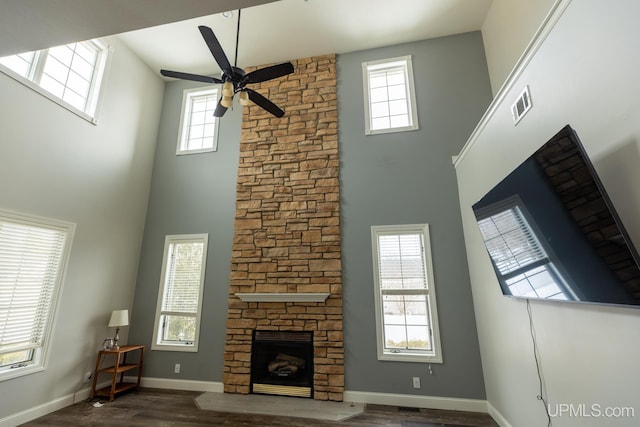 unfurnished living room with dark hardwood / wood-style flooring, a fireplace, ceiling fan, and a high ceiling