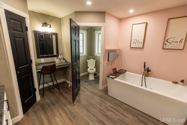 bathroom featuring a tub, hardwood / wood-style floors, and toilet