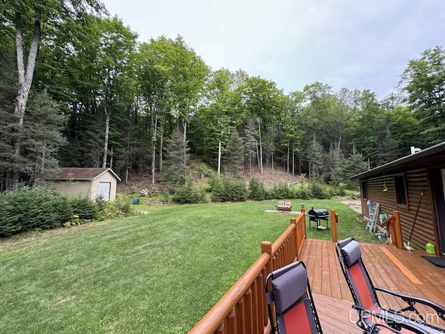 view of yard featuring a wooden deck, a storage unit, and an outdoor fire pit