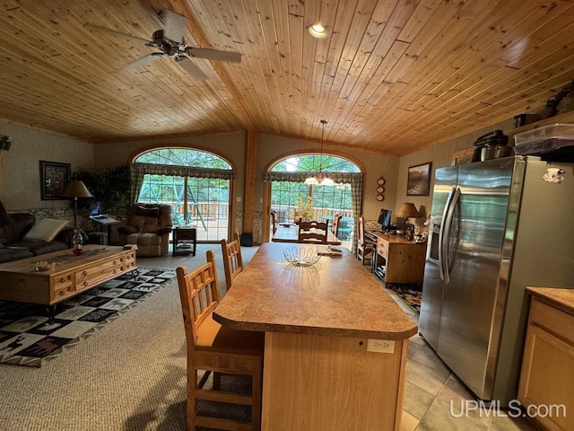 kitchen with light tile patterned flooring, wood ceiling, a center island, vaulted ceiling, and stainless steel fridge