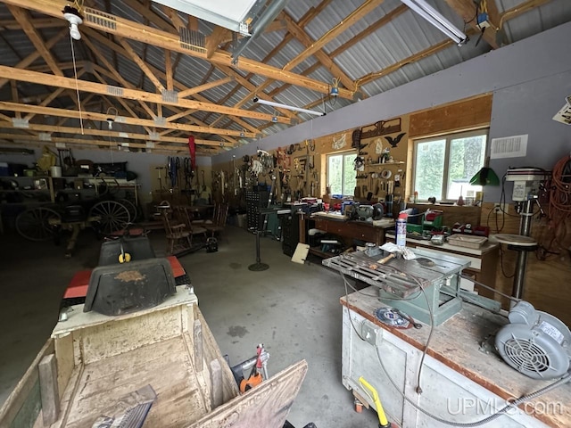 miscellaneous room featuring concrete flooring, vaulted ceiling, and a workshop area