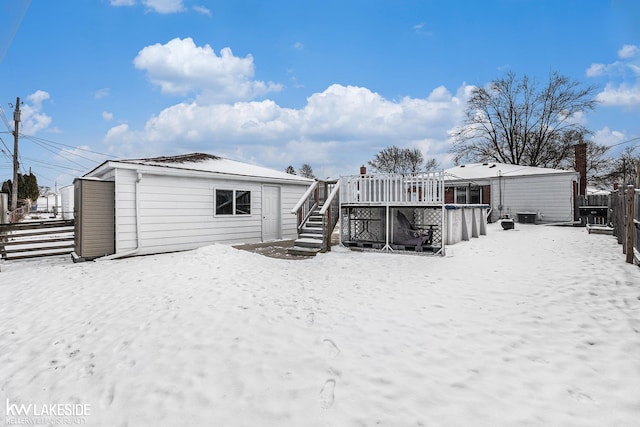 snow covered rear of property with a swimming pool