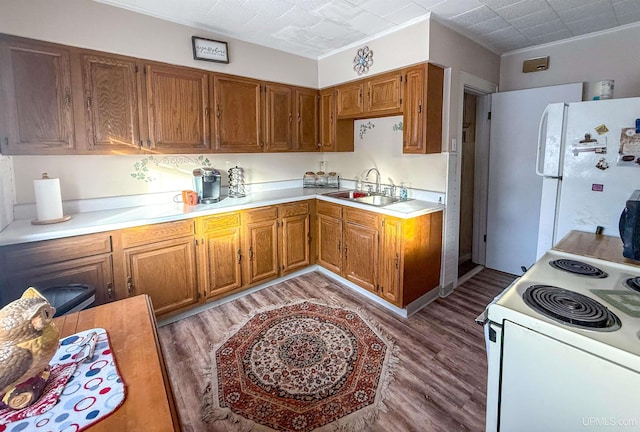 kitchen with white appliances, wood-type flooring, and sink