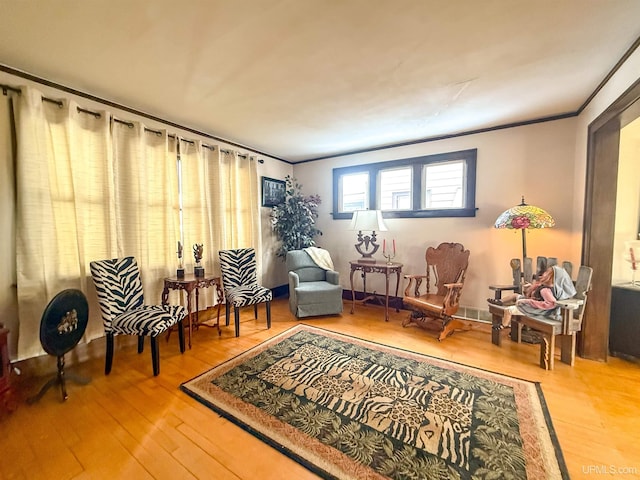 living area featuring hardwood / wood-style flooring and ornamental molding