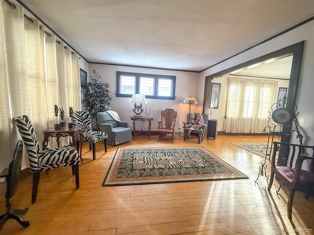 sitting room with ornamental molding and light wood-type flooring