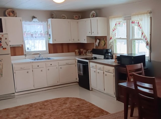 kitchen featuring white refrigerator, white cabinets, sink, and electric range