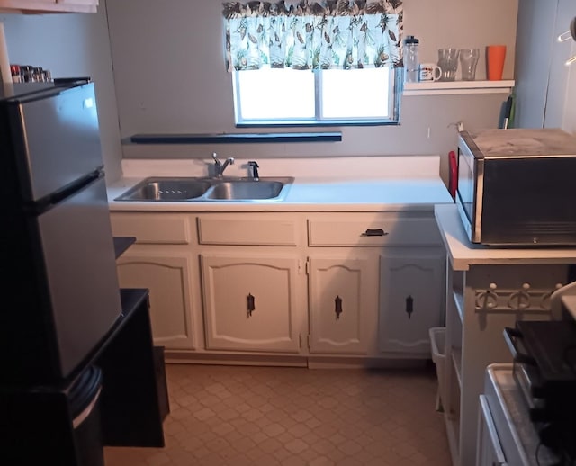 kitchen featuring sink, white cabinets, and refrigerator