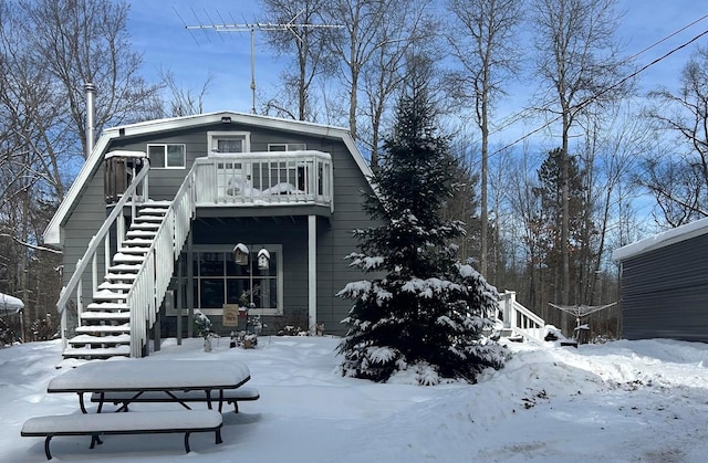 snow covered house featuring a balcony