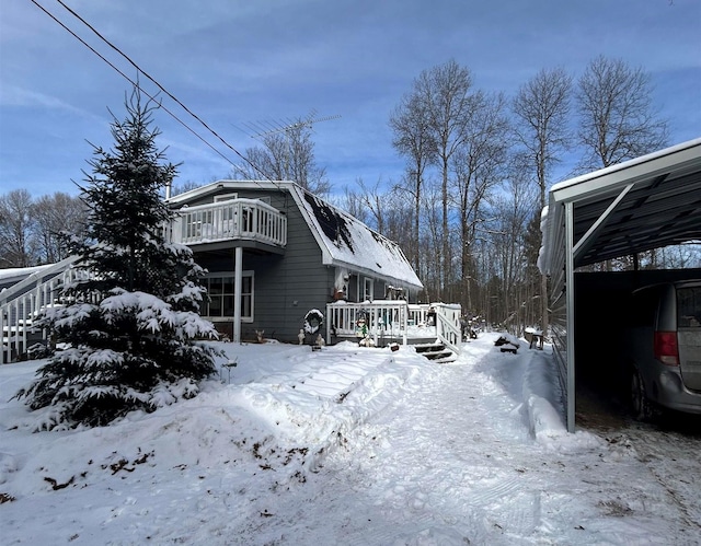 snow covered property featuring a carport, a wooden deck, and a balcony