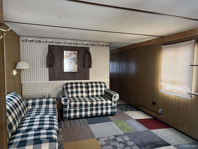 carpeted living room with wooden walls