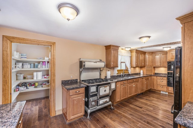 kitchen with dark hardwood / wood-style flooring, sink, black refrigerator, and dark stone countertops