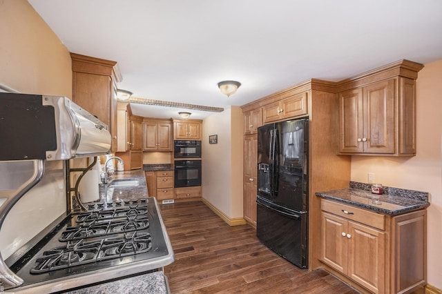 kitchen with sink, dark wood-type flooring, dark stone countertops, black refrigerator with ice dispenser, and cooktop