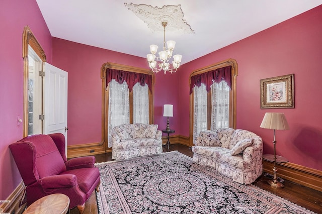 sitting room featuring wood-type flooring, a healthy amount of sunlight, and a chandelier