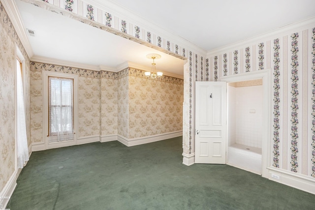 empty room featuring dark colored carpet, crown molding, and a chandelier