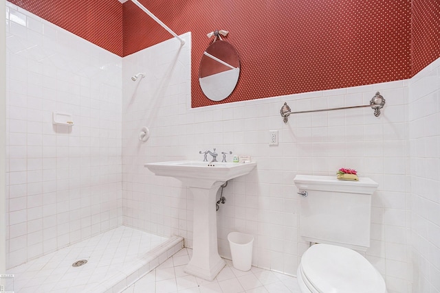 bathroom featuring a tile shower, tile patterned floors, tile walls, and toilet