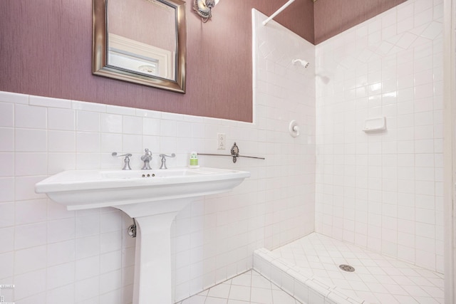 bathroom with a tile shower and tile walls