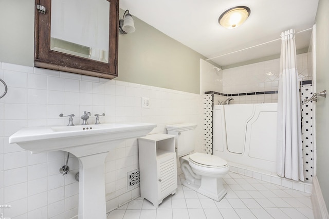 bathroom featuring shower / bath combination with curtain, tile patterned floors, toilet, and tile walls