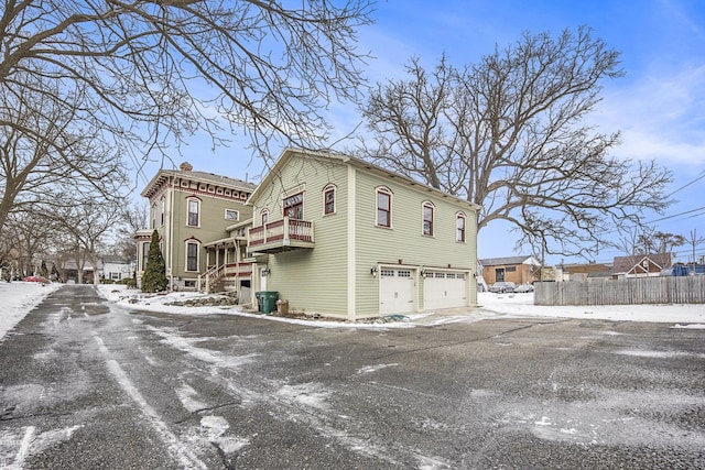 view of snowy exterior featuring a garage and a balcony