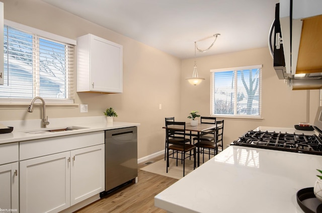 kitchen featuring sink, light hardwood / wood-style flooring, hanging light fixtures, white cabinets, and stainless steel dishwasher